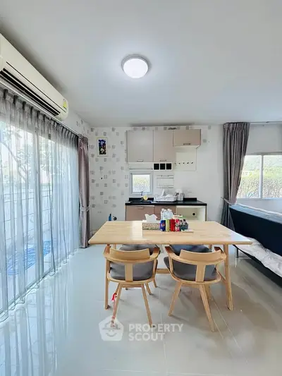 Modern dining area with natural light, sleek furniture, and compact kitchen in open layout.