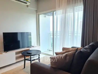 Modern living room with balcony view, featuring sleek furniture and natural light.