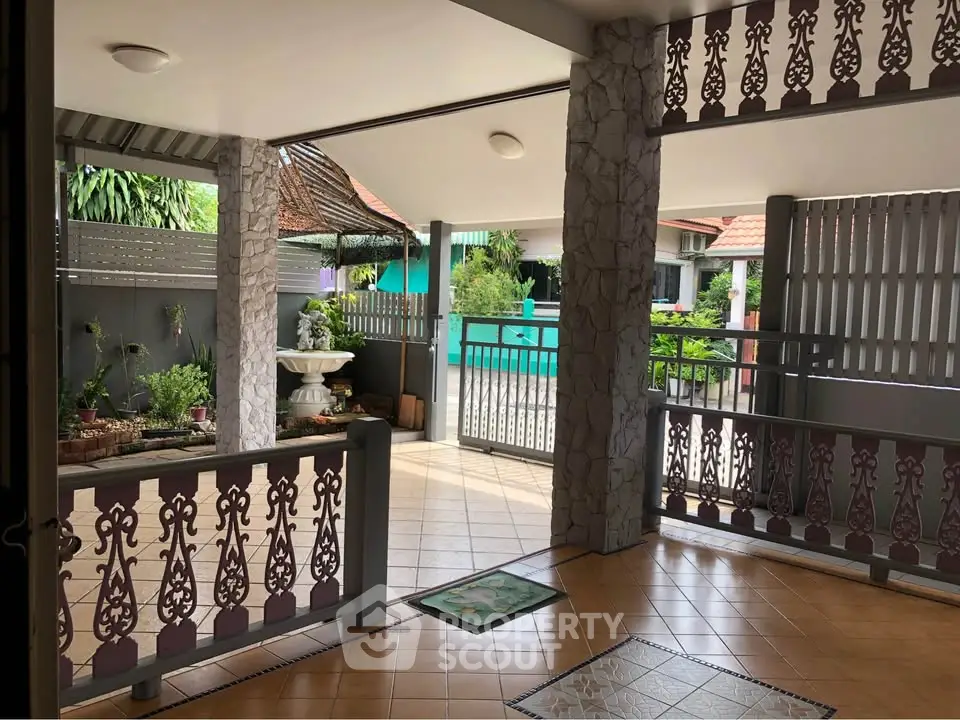 Charming open-air entrance with decorative railings and lush greenery, perfect for welcoming guests.
