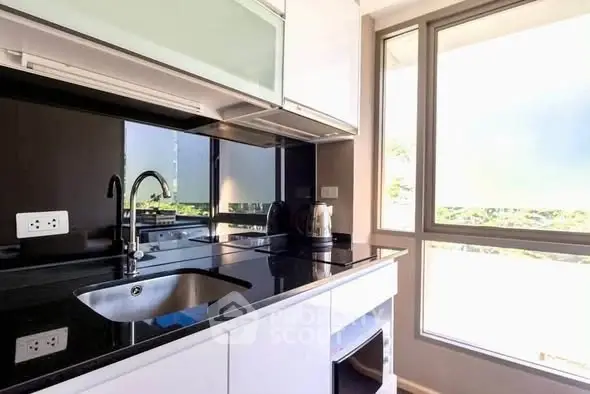 Modern kitchen with sleek black countertops and large window offering natural light.