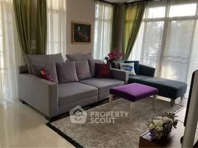 Charming living room with elegant decor, plush seating, and abundant natural light from large windows.