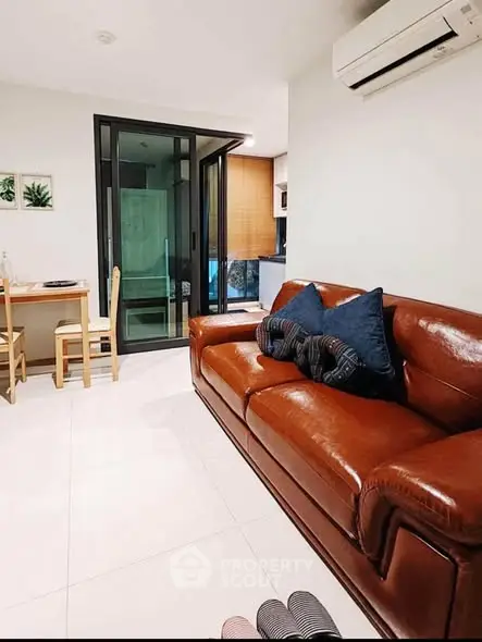 Modern living room with leather sofa and dining area in stylish apartment.