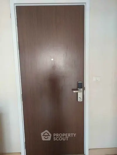 Modern wooden apartment door with electronic lock in a contemporary building.