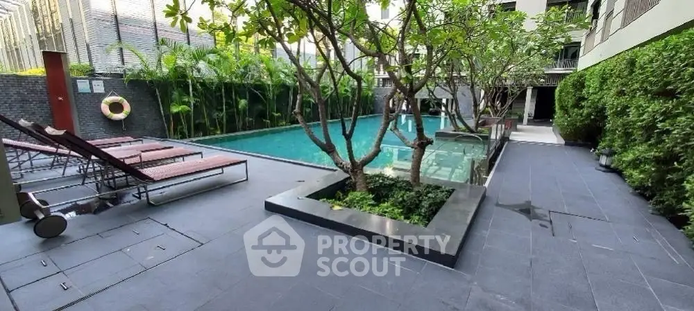 Luxurious modern pool area with lush greenery and sun loungers in a high-end residential complex.