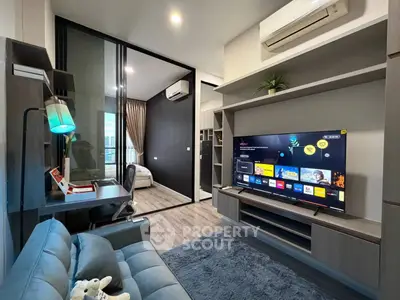 Modern living room with sleek design and large TV, adjacent to a cozy study area.