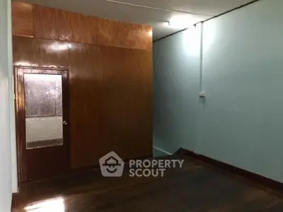 Spacious empty room with wooden flooring and paneling, ideal for customization.