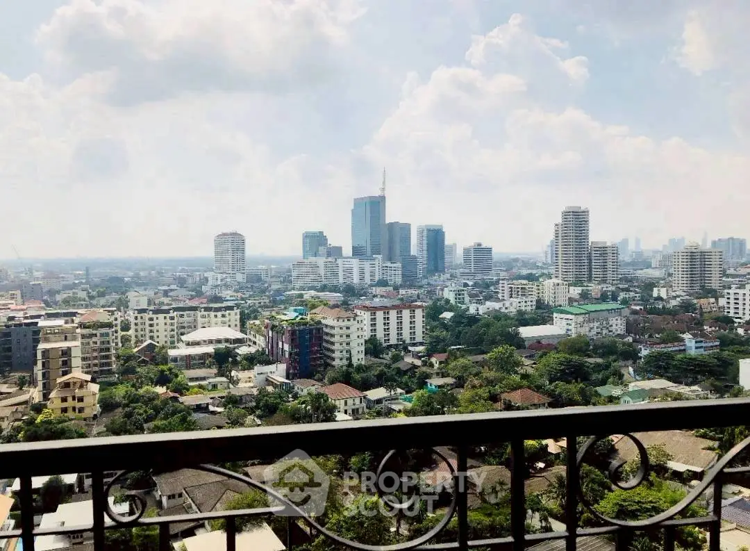 Stunning cityscape view from a high-rise balcony overlooking urban skyline and lush greenery.