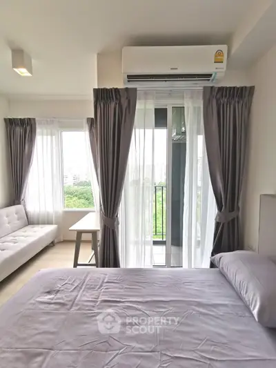 Modern bedroom with balcony view, featuring sleek furniture and abundant natural light.