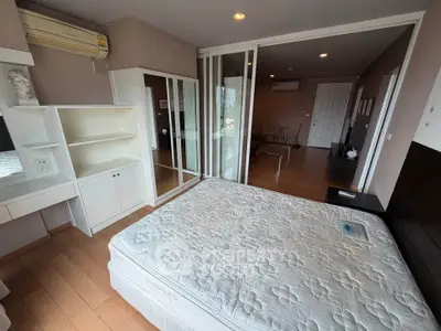 Spacious bedroom with modern furnishings and large mirrored closet in a stylish apartment.