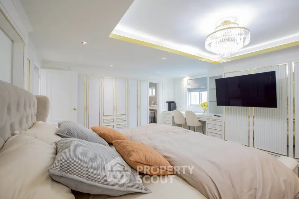 Luxurious bedroom with elegant decor and large TV, featuring plush bedding and stylish lighting.