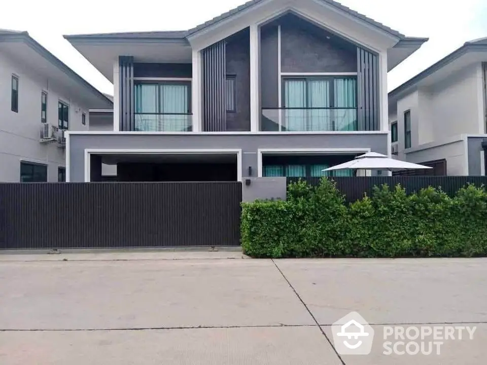 Modern two-story house with sleek design and lush greenery in a suburban neighborhood.