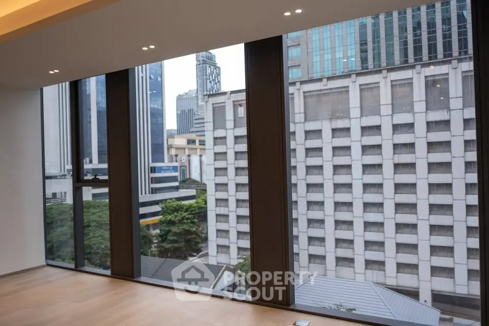 Spacious modern living room with floor-to-ceiling windows offering stunning city views.