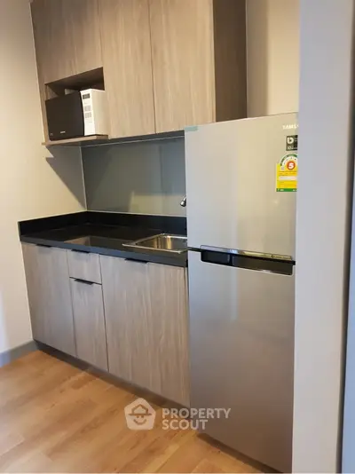 Modern kitchen with sleek cabinetry and stainless steel fridge in a compact layout.
