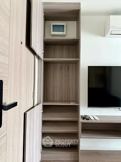 Modern apartment interior with stylish wooden storage and wall-mounted TV, showcasing efficient use of space.
