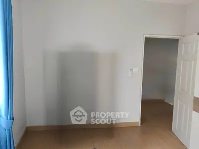 Minimalist empty room with wooden flooring and blue curtains