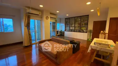 Spacious living room with hardwood floors and large windows offering city views.
