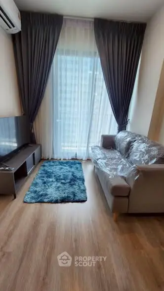 Modern living room with sleek furniture and large window, perfect for urban living.