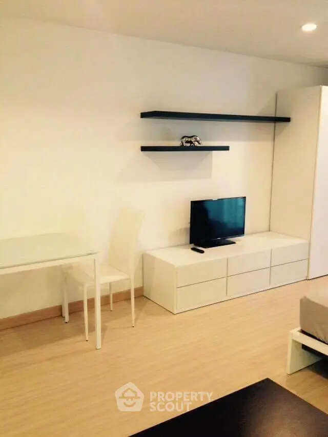 Modern minimalist living room with sleek white furniture and wall-mounted shelves
