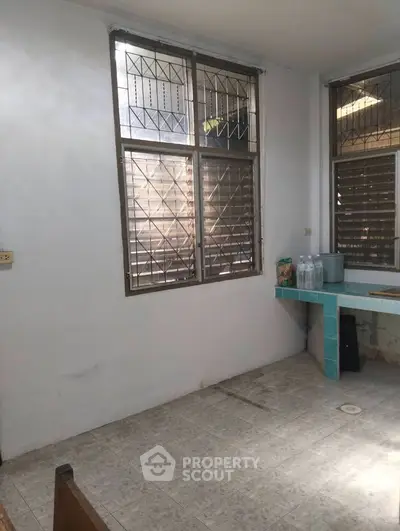 Spacious room with tiled floor and large windows, ideal for renovation or customization.