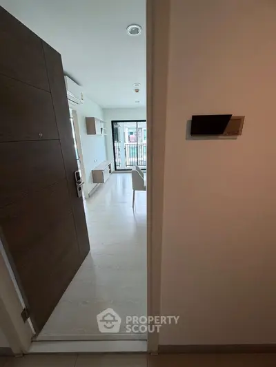 Modern apartment entrance leading to a bright living area with sleek furnishings and balcony view.