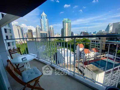Stunning cityscape view from a spacious balcony with outdoor seating, perfect for relaxation.