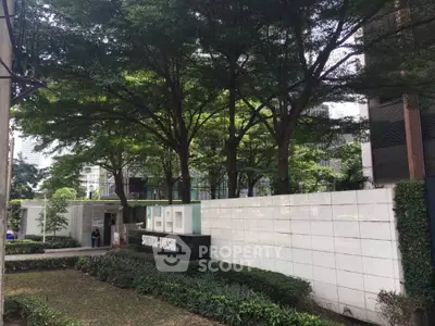 Modern building entrance with lush greenery and stylish signage at Ideo Sathorn Thapra.