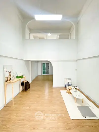 Spacious two-story living area with modern decor and wooden flooring, perfect for stylish urban living.