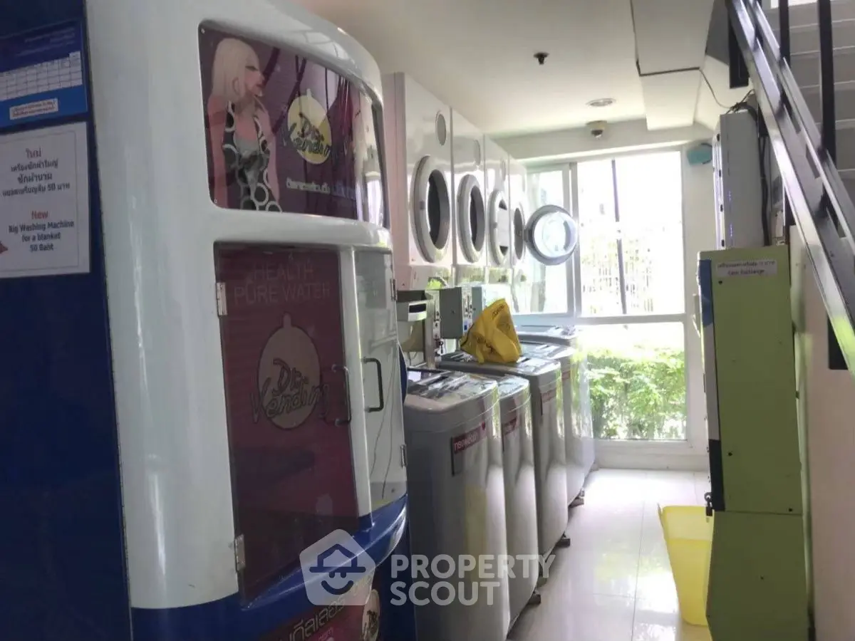 Modern laundry room with multiple washing machines and vending machines under natural light.