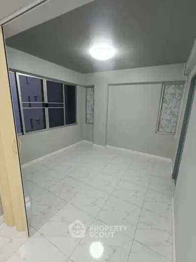 Spacious empty room with large windows and elegant tiled flooring, perfect for customization.