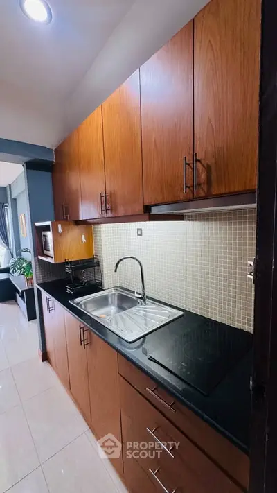 Modern kitchen with sleek wooden cabinets and black countertop in stylish apartment.