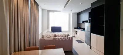 Modern living room with open kitchen layout and large windows in a stylish apartment.