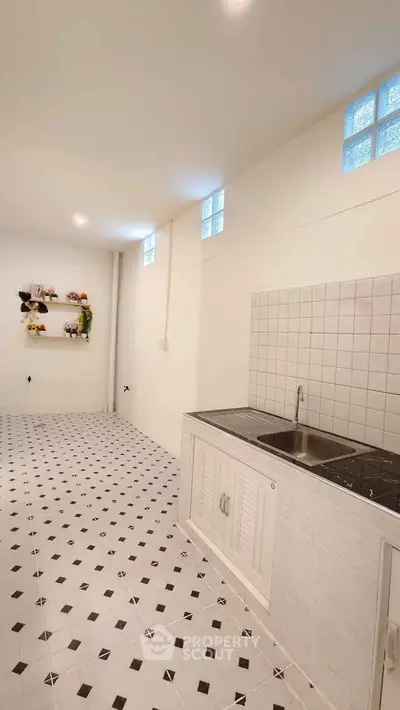 Spacious kitchen with tiled floor and modern sink in a bright, minimalist design.