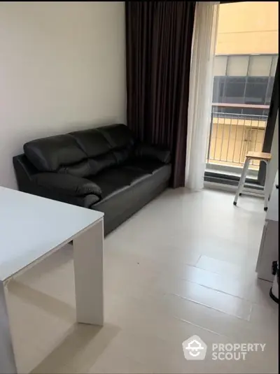 Modern living room with black leather sofa and large window