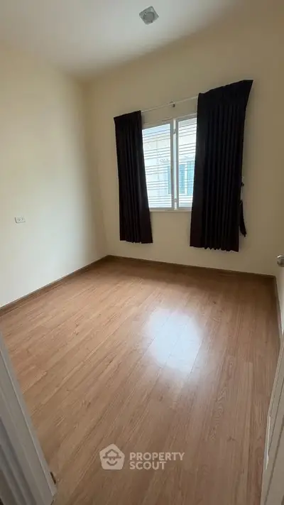 Spacious empty bedroom with wooden flooring and large window