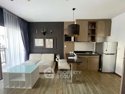 Modern open-layout living room with kitchen, featuring sleek furniture and natural light.