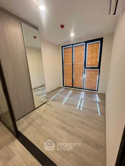 Modern bedroom with large mirrored wardrobe and natural light
