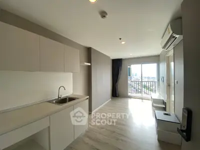Modern open-plan living room with kitchen and balcony view, featuring sleek cabinetry and natural light.