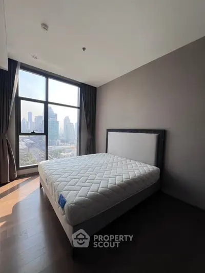 Spacious bedroom with city view and large window in modern apartment