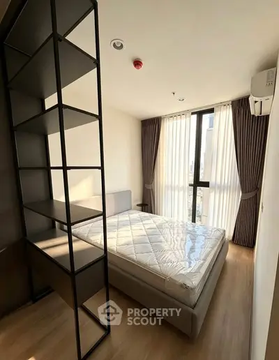 Modern bedroom with large window and stylish shelving in a contemporary apartment.