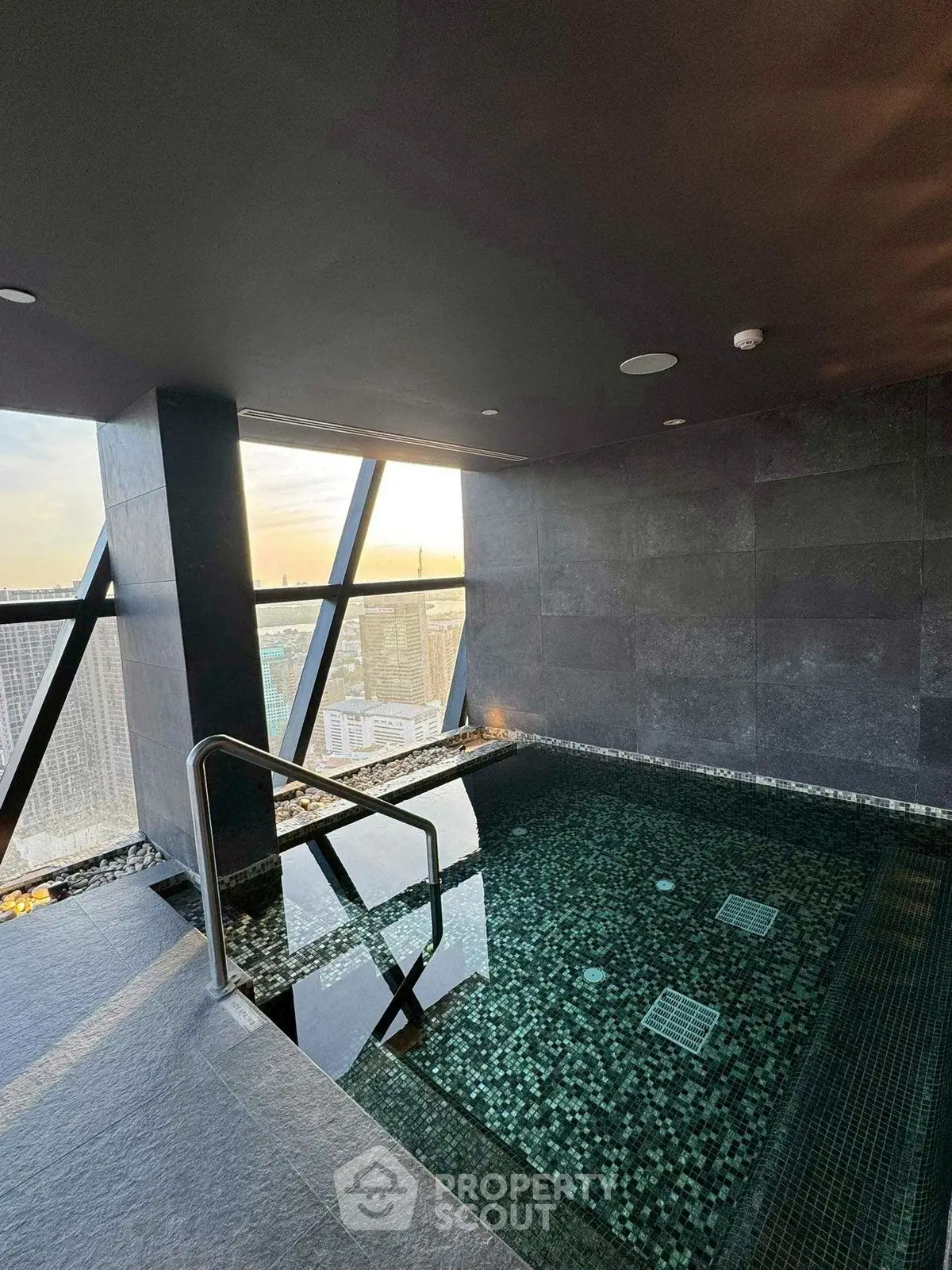 Luxurious rooftop pool with stunning city view at sunset, perfect for relaxation and leisure.