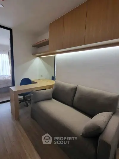 Modern study room with sleek desk, comfortable sofa, and ample storage in a stylish apartment.