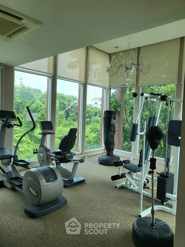 Spacious gym with modern equipment and scenic green views through large windows.
