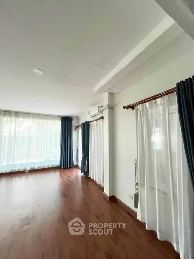 Spacious living room with hardwood floors and large windows for natural light.