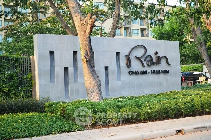 Modern condominium entrance with lush greenery and stylish signage.