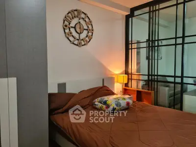 Cozy bedroom with modern decor and glass partition, featuring a stylish wall clock and warm lighting.