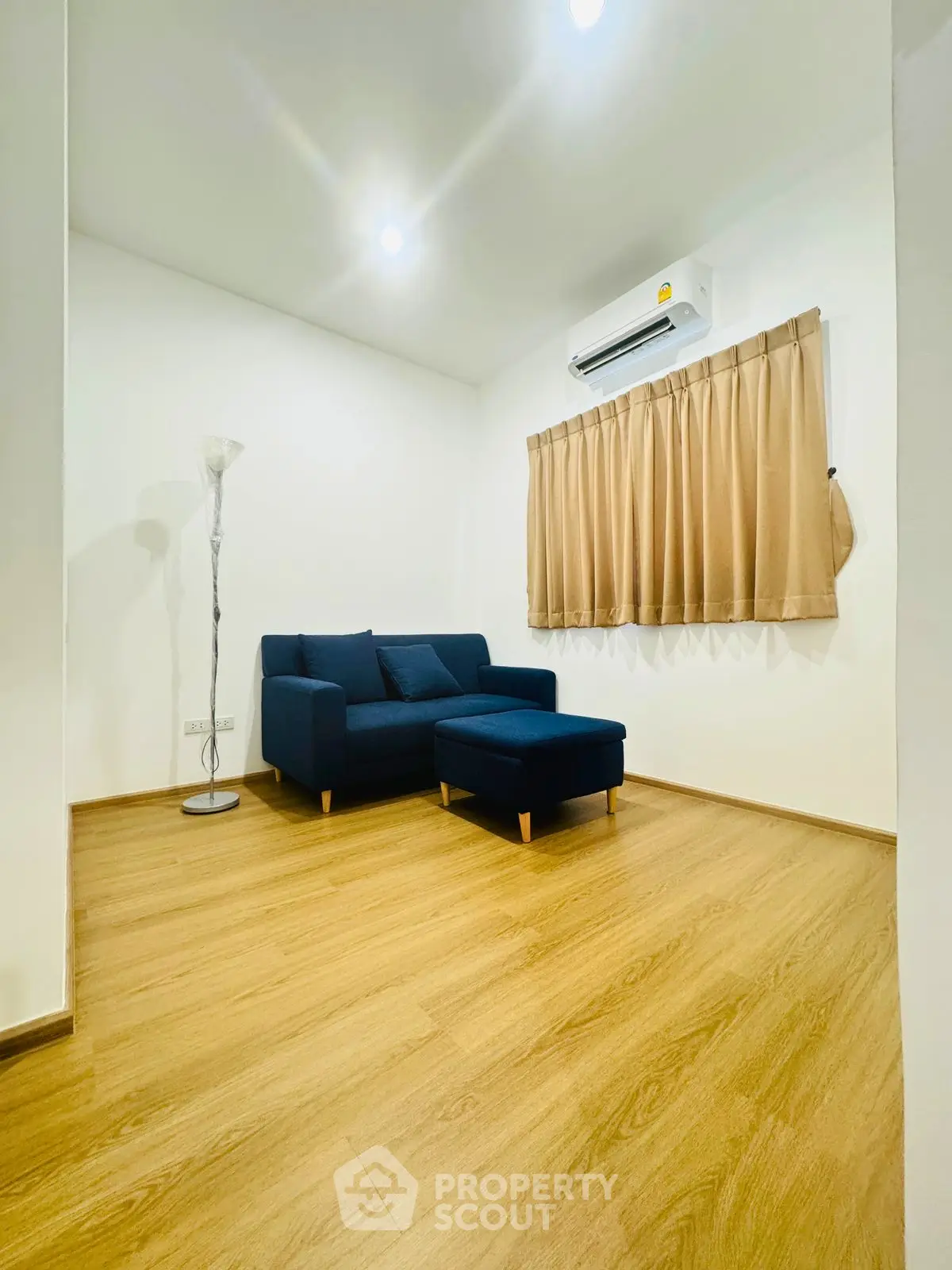 Cozy living room with modern sofa and wooden flooring, perfect for relaxation.