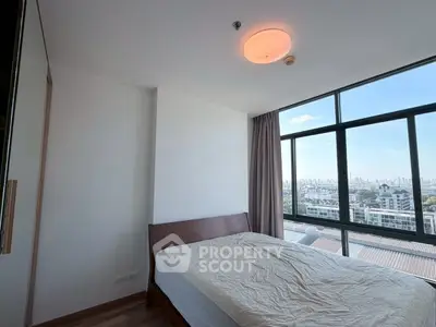 Spacious bedroom with large windows offering stunning city views in modern apartment.