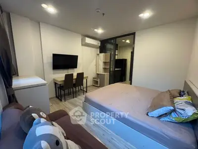 Modern studio apartment with cozy bed and dining area, featuring sleek design and ample lighting.