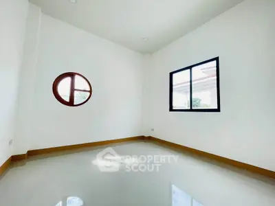 Spacious minimalist room with unique round window and bright natural light
