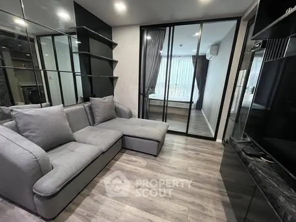Modern living room with sleek design and glass partition leading to bedroom